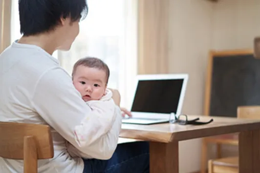 子守をしながらテレワークする父親