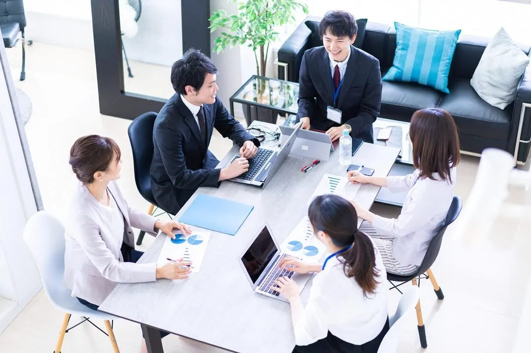 従業員の学びによる企業変革を象徴する、グラフや資料を見ながら会議する5人のビジネスパーソン