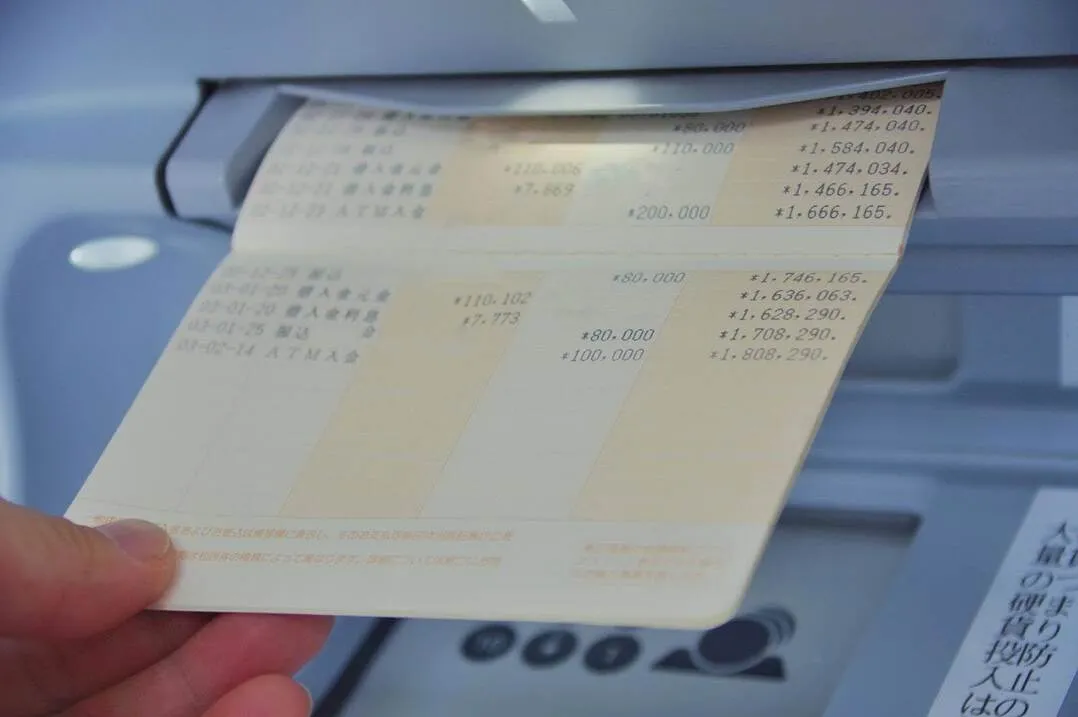 通帳記帳中の手元とATM、iDeCoは60歳まで引き出せないことを示唆