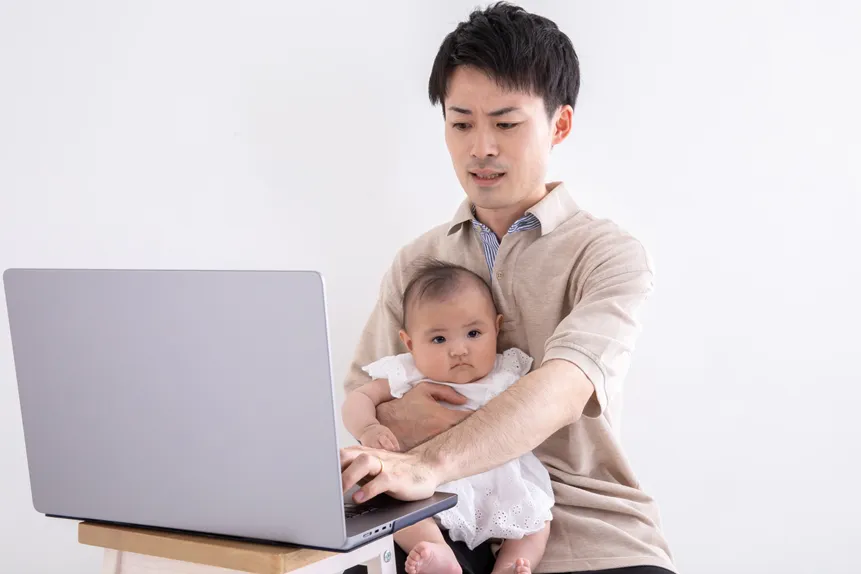 子守をしながらテレワークをしている父親