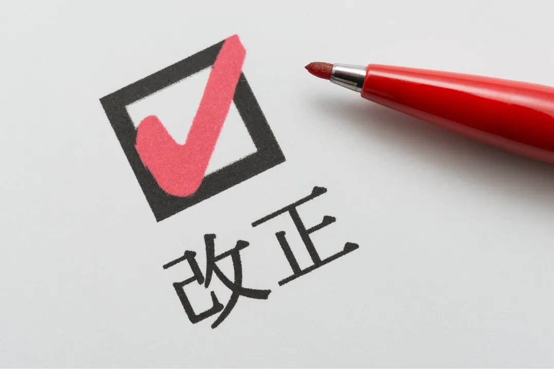 中小企業保護を目的とした下請法改正の説明に関連するイメージ。赤ペンとチェックマークで「改正」を強調。