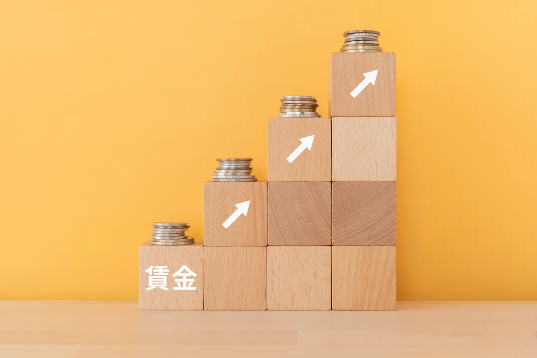 物価上昇を上回る賃金改善を視覚的に表現した、賃金ブロックと段階的に積まれた硬貨の画像