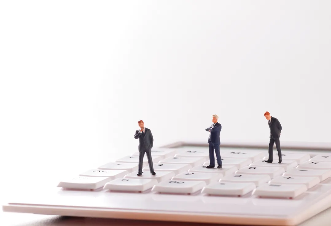 電卓の上に乗る男性たち