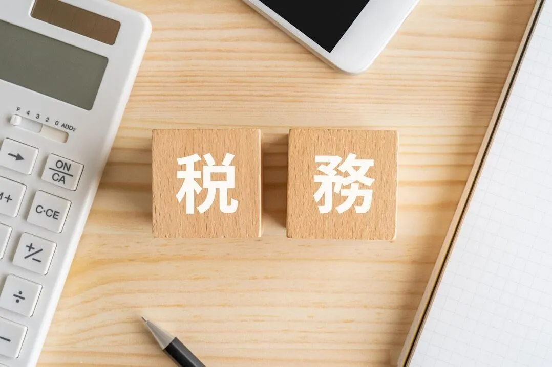 税務処理を象徴する木製ブロックと事務用品、法人税法の修繕費判定のイメージ