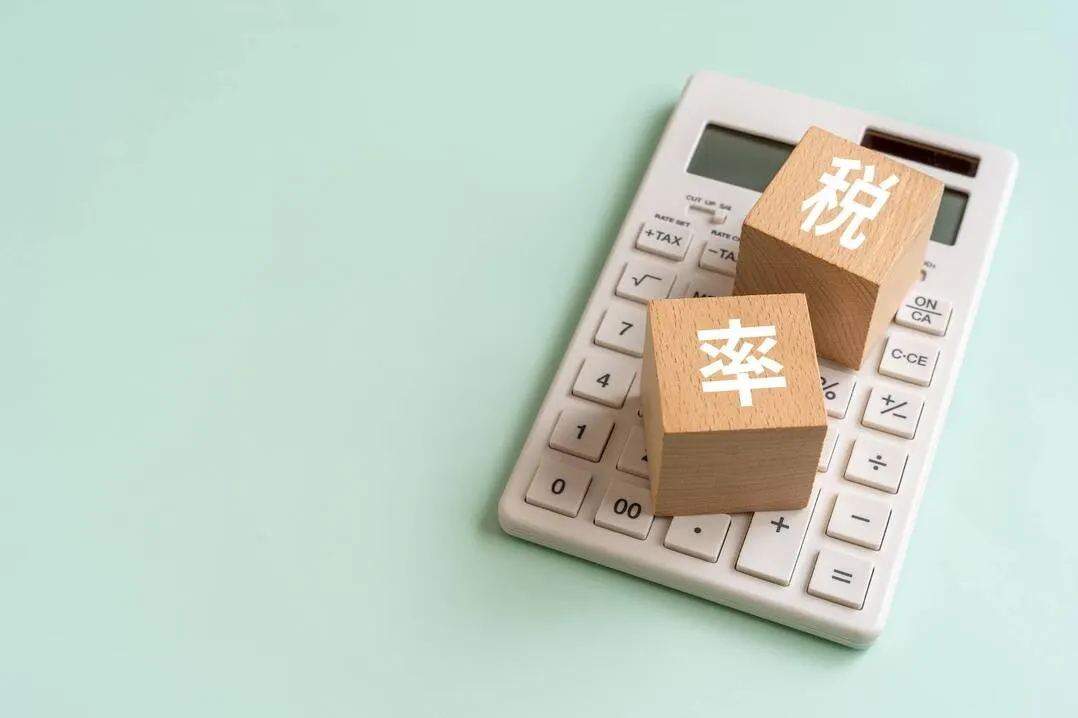 税率の文字が書かれた木製ブロックと電卓、延滞税の計算をイメージ
